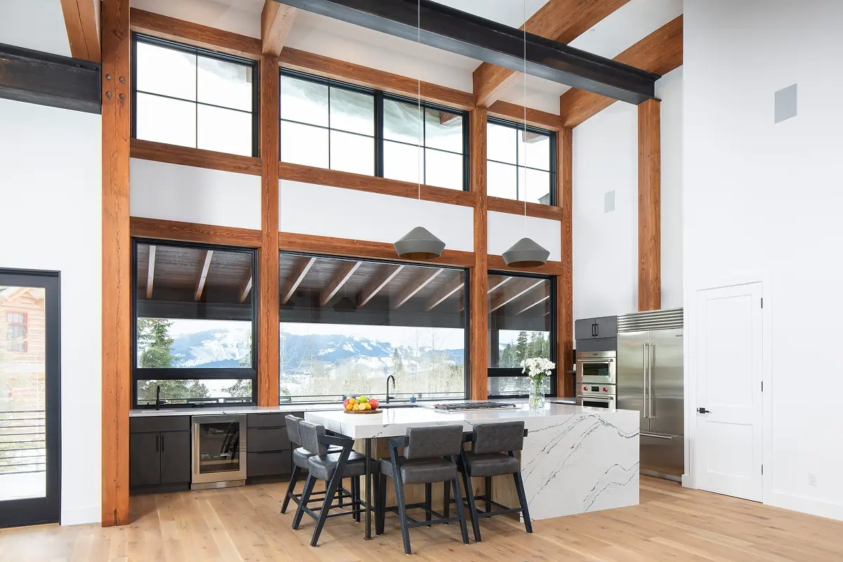 Luxury kitchen with exposed timber beams, marble island, and large windows framing Crested Butte’s snow-covered landscape.