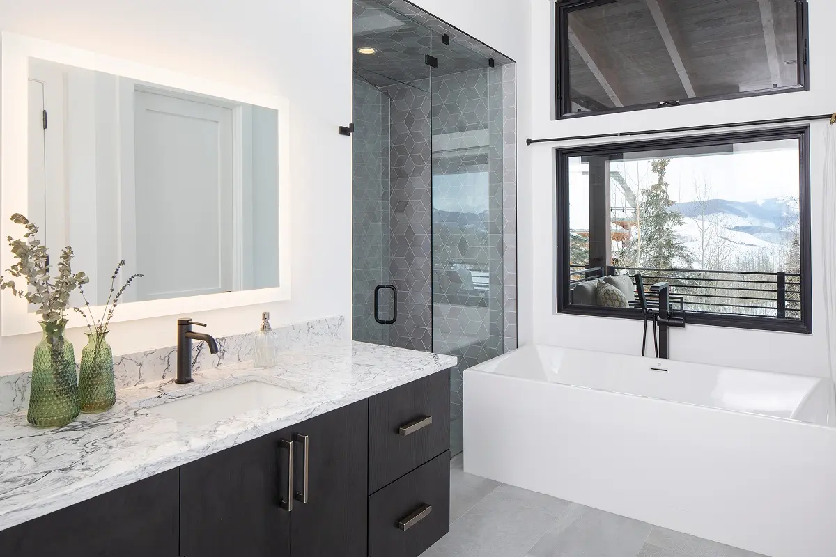 Elegant bathroom with marble vanity, glass shower, and picture windows offering mountain views in Crested Butte, Colorado.