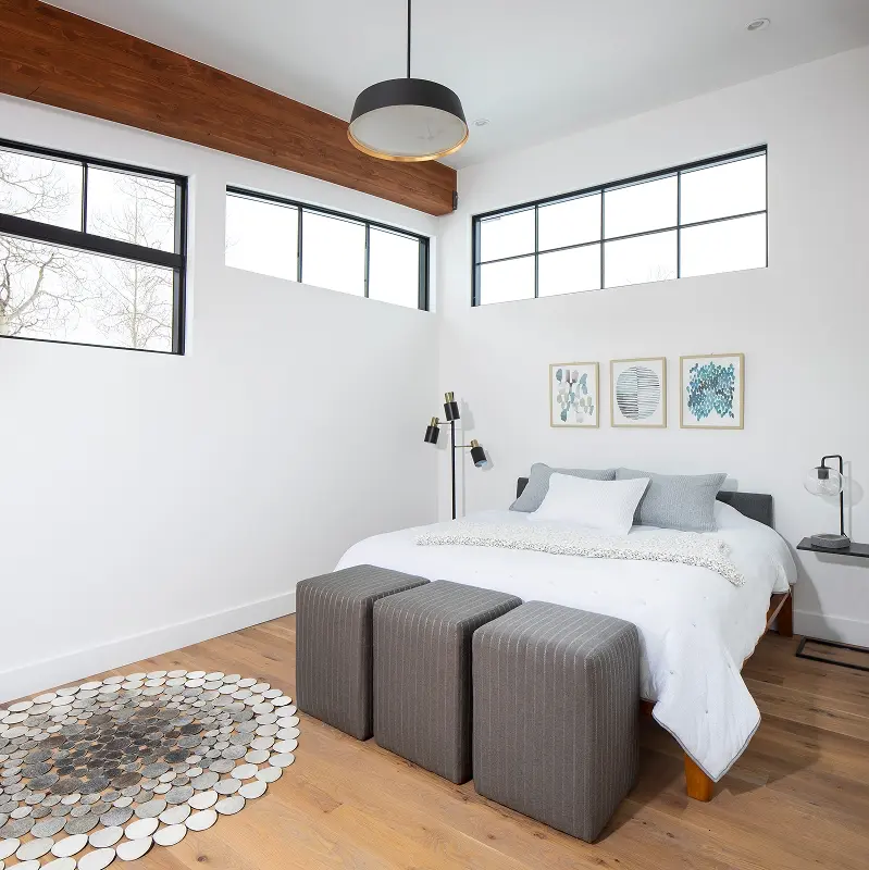 Guest bedroom with minimalist decor, high windows, and natural light in a modern mountain home in Crested Butte.